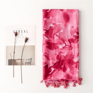 Detail of pink watercolor splash scarf with bohemian tassels on a minimalist background