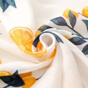 Detail of soft white linen scarf with vibrant orange citrus slices and green leaves print