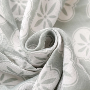 Macro shot of light green fabric with white floral patterns and bohemian details