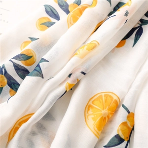Close-up detail of lightweight cotton linen scarf with vibrant orange fruit print patterns