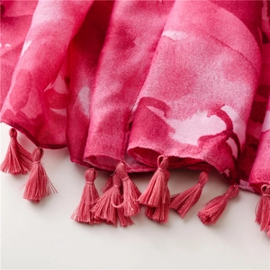 Macro detail of magenta artistic print fabric with delicate bohemian tassel trim