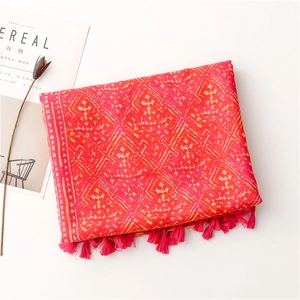 Close-up of bright red bohemian shawl with yellow geometric patterns and fringed edges