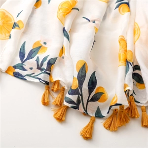 Detailed close-up of summer cotton linen scarf with yellow lemon print and fringe tassels