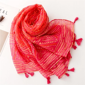 Close-up of bohemian red scarf with yellow geometric patterns and tassel fringe details