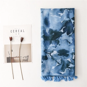 Detail of blue ink-wash print scarf with delicate tassels and lightweight fabric texture