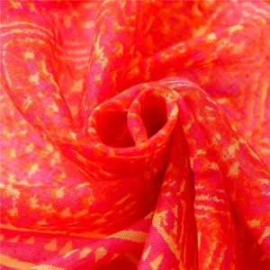 Close-up detail of lightweight red bohemian scarf fabric with geometric mesh texture