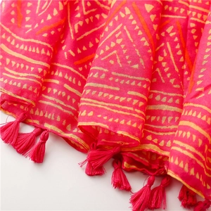 Close-up of pink bohemian scarf featuring orange geometric patterns and tassel edges