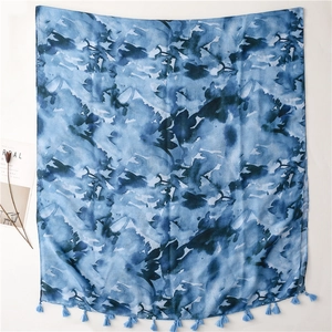 Detail of artistic blue ink-wash scarf with soft fringe trim and lightweight texture