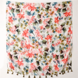 Détail d'une écharpe bohème aux fleurs corail et pompons vert olive en coton et lin