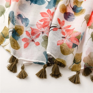 Détail d'une écharpe ethnique à fleurs montrant la texture coton lin et les pompons verts