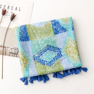 Detail of bohemian scarf showing geometric patterns and fringe tassels on a white background