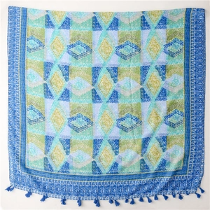 Detail of bohemian shawl featuring blue and green geometric patterns with fringe edges