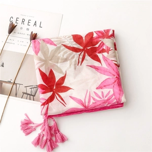 Détail d'une écharpe à motif de feuilles d'érable rouges et franges roses douces