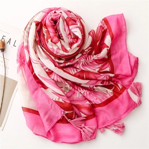 Détail de l'écharpe rose à imprimé feuilles tropicales avec franges et texture soie