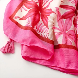 Vue détaillée de l'imprimé floral tropical sur l'écharpe rose avec glands à franges