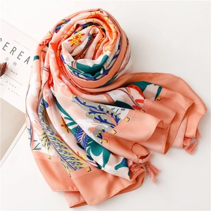 Detail of coral pink floral silk scarf with palm leaf prints and elegant tassel edges