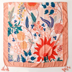 Close-up of floral silk scarf with orange dahlia prints and decorative corner tassels