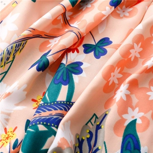 Close-up of soft floral silk scarf with colorful bird prints and fine twill texture
