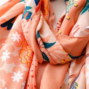 Detail of silk scarf showing orange fabric with white flowers and twill texture