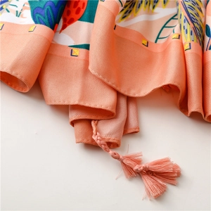 Detail of tropical floral print silk shawl with handmade orange fringe tassels