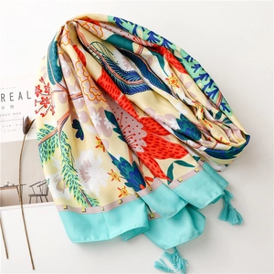 Detail of floral silk scarf showing tropical leaf patterns and blue fringe tassels