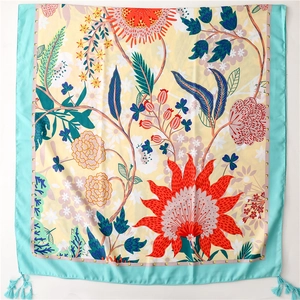 Detailed view of floral beach shawl with red sunflower pattern and turquoise tassels