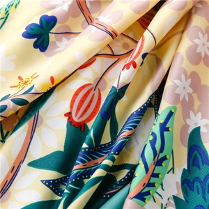 Macro detail of silk floral scarf showing intricate white blossoms and soft satin texture