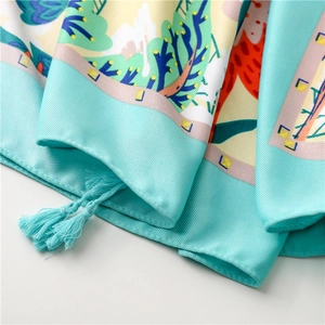 Close-up of silk scarf with floral print, twill texture and decorative tassels