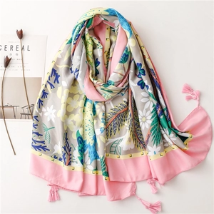 Grey floral beach shawl with yellow flowers, green leaves and pink tassels on white backdrop