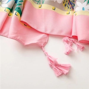 Macro shot of pink floral silk shawl fabric with yellow trim and tassel details