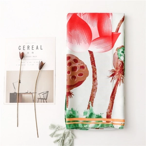 Detail of floral silk scarf featuring red lotus prints and grey tassels on white fabric
