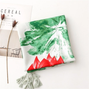 Detail of silk scarf featuring green abstract prints and elegant light teal tassels