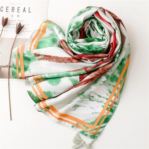 Detail of silk scarf showing abstract print and soft fringed edges on a clean background