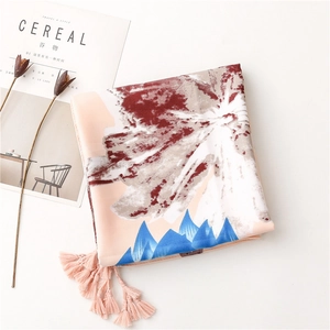 Detail of floral printed scarf with pink tassels next to a decorative magazine