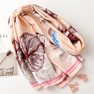 Detailed view of floral silk scarf with elegant fringe trim and striped border pattern