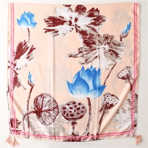 Close-up of silk scarf featuring blue lotus prints and pink tassels on a white background