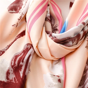 Detail of peach pink silk scarf featuring lotus patterns and fine satin weave texture
