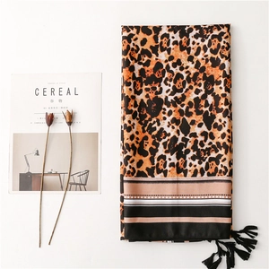 Detail of leopard print scarf with bohemian fringe and striped border on white surface