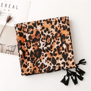 Detail shot of leopard print scarf with black fringe tassels on a minimalist background