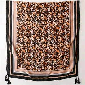 Detail view of leopard print silk scarf with geometric borders and black tassels