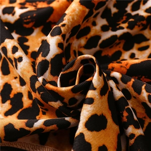 Close-up of leopard print silk scarf fabric showing soft knit texture and fringe detail
