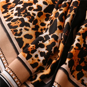 Detailed view of leopard print silk scarf with smooth fabric texture and border details