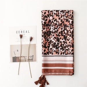 Detail of leopard print silk scarf with fringe tassels next to lifestyle magazine