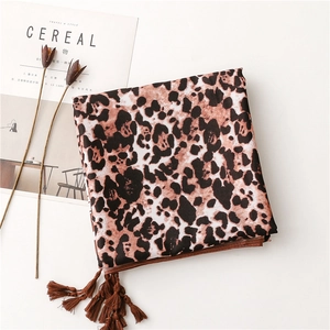 Detail of leopard print silk scarf featuring brown handmade tassels and silky fabric texture