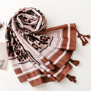 Detail shot of leopard print silk scarf with elegant brown tassel edges and soft texture