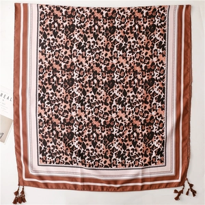 Close-up of leopard print silk scarf featuring fringe details and striped borders