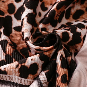 Close-up of leopard print silk scarf with luxury twill texture and logo detail
