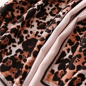 Macro shot of leopard print silk scarf fabric showing glossy texture and elegant drape
