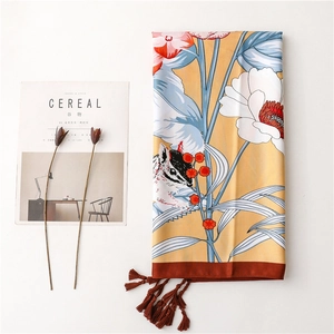 Detailed close-up of yellow floral scarf with squirrel motif and fringe tassels