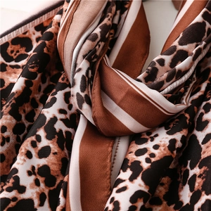 Macro detail of silk scarf showing leopard print, stripes and soft fabric texture